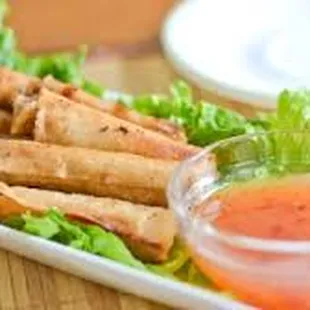 a plate of fried spring rolls with dipping sauce