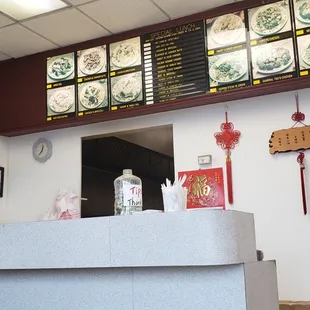 a restaurant counter with a menu on the wall