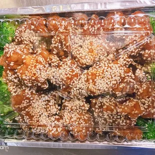 a tray of sesame chicken and broccoli