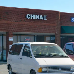 a white van parked in front of a chinese restaurant