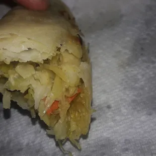 a hand holding a pastry with sauerkraut and carrots