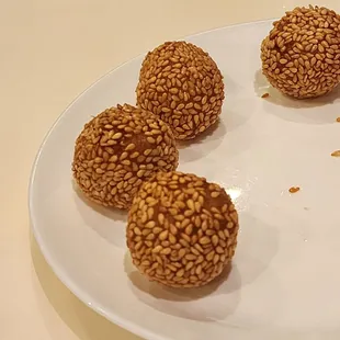 four sesame balls on a white plate