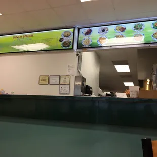 a restaurant counter with a menu on the wall
