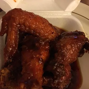 chicken wings in sauce in a styrofoam container