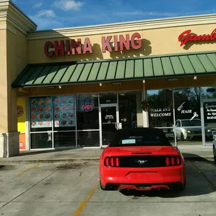 a red sports car parked in front of a chinese restaurant