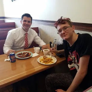 two men sitting at a table with plates of food