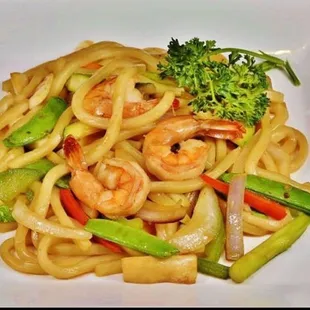 a plate of noodles with shrimp and vegetables