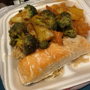 a takeout container with a sandwich and broccoli