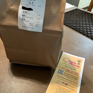 a brown paper bag and a receipt on a table