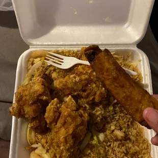 a hand holding a fork over a container of food