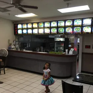 a little girl standing in front of a restaurant counter