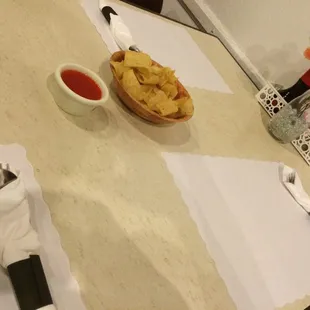 a table setting with a bowl of chips and a bowl of tomato sauce