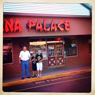 a man and two children standing in front of a restaurant