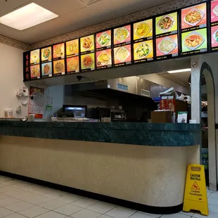 a restaurant counter with menus on the wall