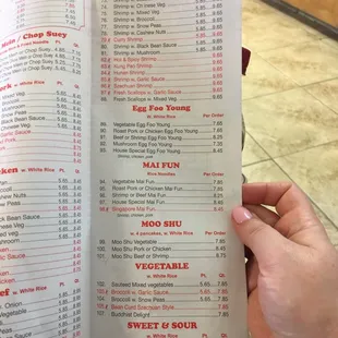 a hand holding a menu in a restaurant