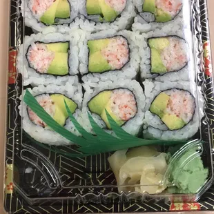a tray of sushi rolls with avocado