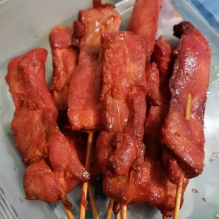 meat skewered on skewers in a plastic container