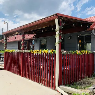 a red picketed fence with sunflowers