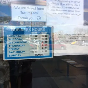 a business hours sign in a window