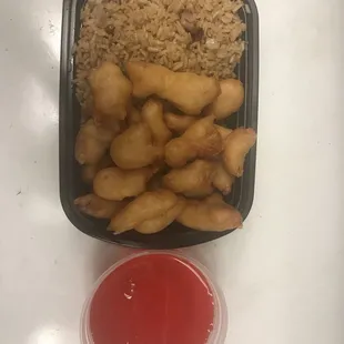 a container of fried chicken and rice with a side of ketchup