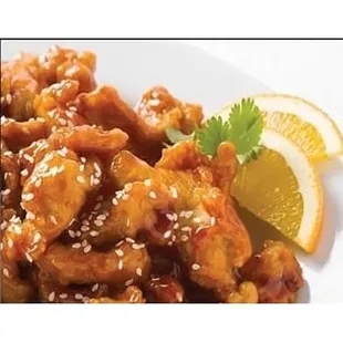 a plate of chicken with sesame seeds and a slice of lemon