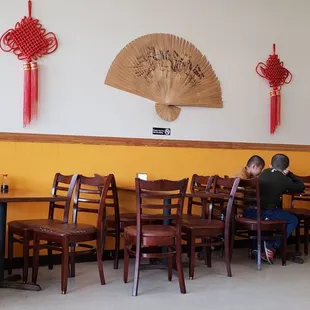 a woman sitting at a table with a fan on the wall