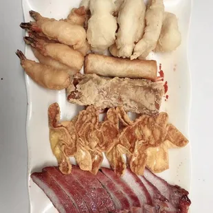 a plate of food that includes meat, shrimp, and other foods
