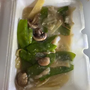 a white styrofoam container with mushrooms and snow peas