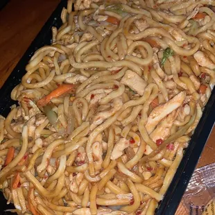 a pan of noodles with chicken and vegetables