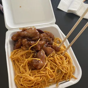 a take out container with noodles and meat