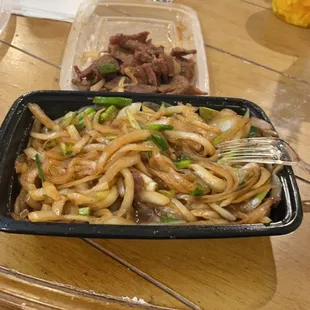 a tray of noodles and meat on a table