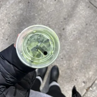a person holding a cup of green tea