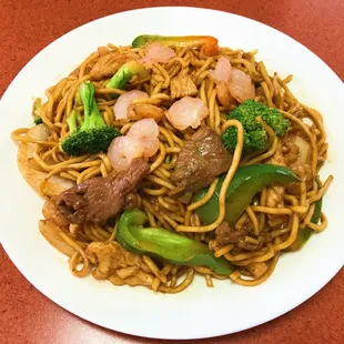 a plate of noodles with shrimp and broccoli