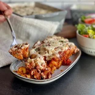 a plate of lasagna and a bowl of salad