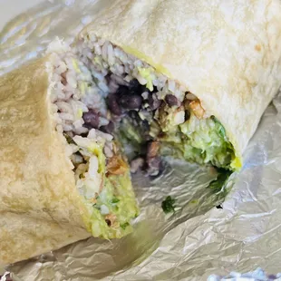 Burrito consisting of lettuce, white cilantro rice, chicken, guacamole, picó de gayo, black beans, and cheese.