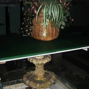 a plant in a basket on top of a fountain