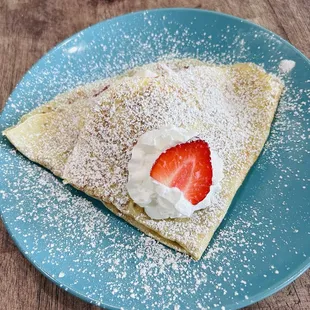 a strawberry and cream crepe on a blue plate