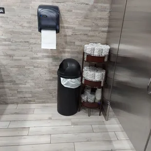 a trash can and toilet paper dispenser