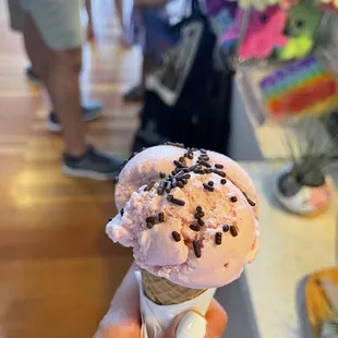 a hand holding an ice cream cone with sprinkles