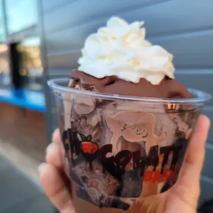 a hand holding a cup of dessert