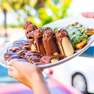 a person holding a plate of desserts