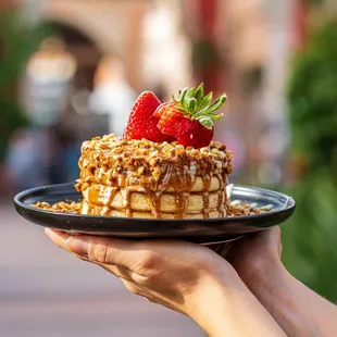 a person holding a plate with a dessert on it
