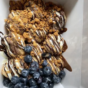 Cream puffs drizzled with milk, dark, white chocolate and cookie butter crumble.