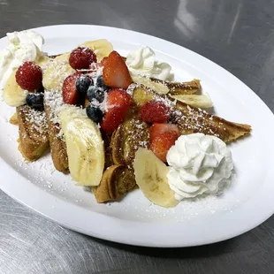 a plate of french toast with strawberries, bananas, and strawberries
