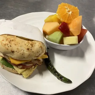 a plate of food with a sandwich and a bowl of fruit