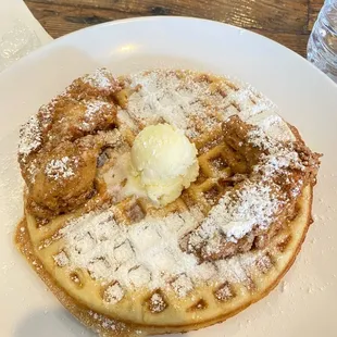 a stack of waffles with butter and powdered sugar