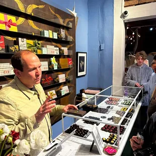 a man standing at a counter in a chocolate shop