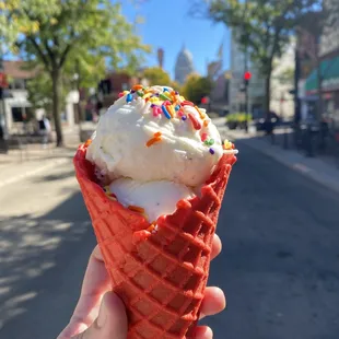 a hand holding an ice cream cone with sprinkles