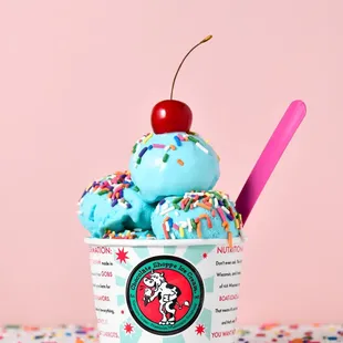 a cup of ice cream with sprinkles and a cherry on top