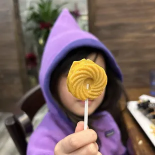 a little girl holding a candy lollipop